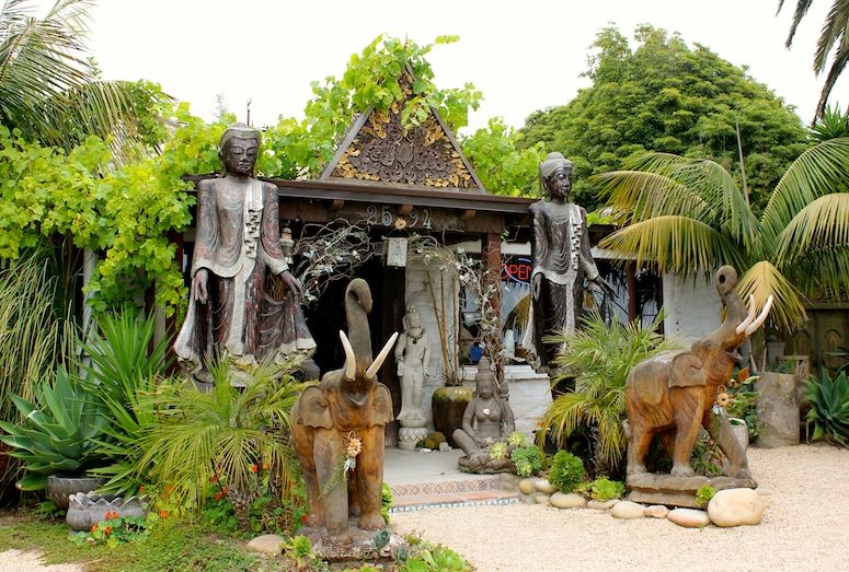The front of Sacred Space in Summerland CA, with wooden statues of the Buddha and elephants surrounded by lush foliage
